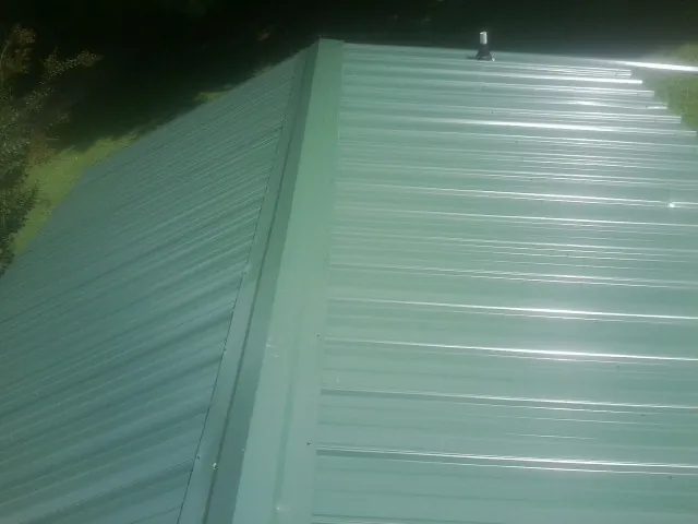 New green metal panels meeting at the ridge of a roof — Flat Roof Repair work by our crew in Camden